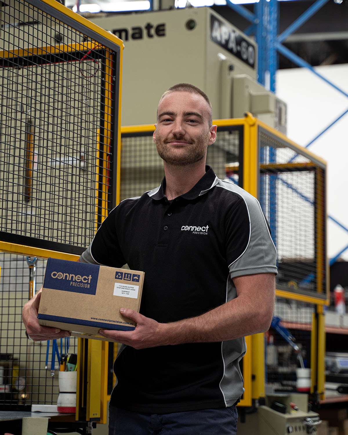 A handsome worker holding a box in a factory